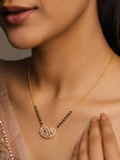 Woman wearing gold-plated black bead mangalsutra with CZ paisley pendant against bare neckline