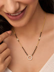 Woman wearing gold-plated CZ halo pendant mangalsutra with black beads against a cream outfit
