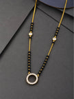Gold-plated black bead mangalsutra with open circle CZ pendant laid flat on dark grey surface