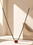 Full-length mangalsutra suspended in a V-shape against a neutral beige background highlighting the CZ pendant