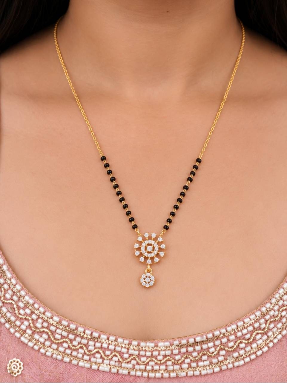 Model wearing gold-plated CZ mangalsutra with black bead strands over a pink embroidered ethnic outfit