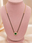 Gold-plated mangalsutra with emerald green CZ pendant displayed on a pink jewellery bust