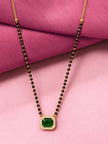 Black bead gold-tone mangalsutra with square green stone pendant on pink fabric background