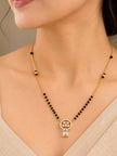 Woman wearing gold-plated CZ mangalsutra with black beads over a beige saree neckline