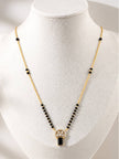 Gold-plated black bead mangalsutra with CZ circular pendant and black emerald-cut drop displayed on white jewellery bust