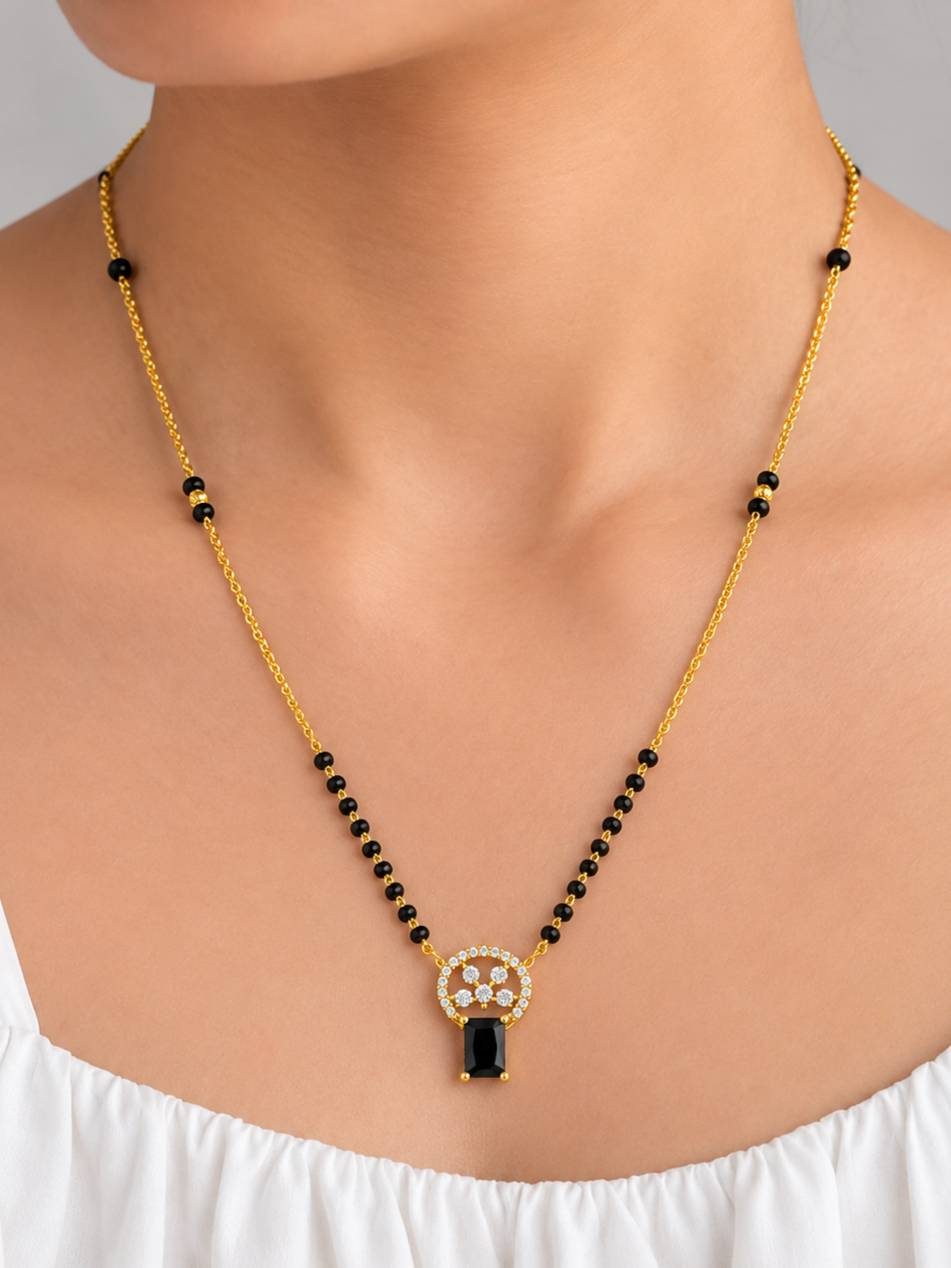 Model wearing gold-plated black bead CZ mangalsutra over white top showing pendant at neckline