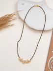 CZ floral mangalsutra laid flat on white surface beside a decorative shell and dried grass