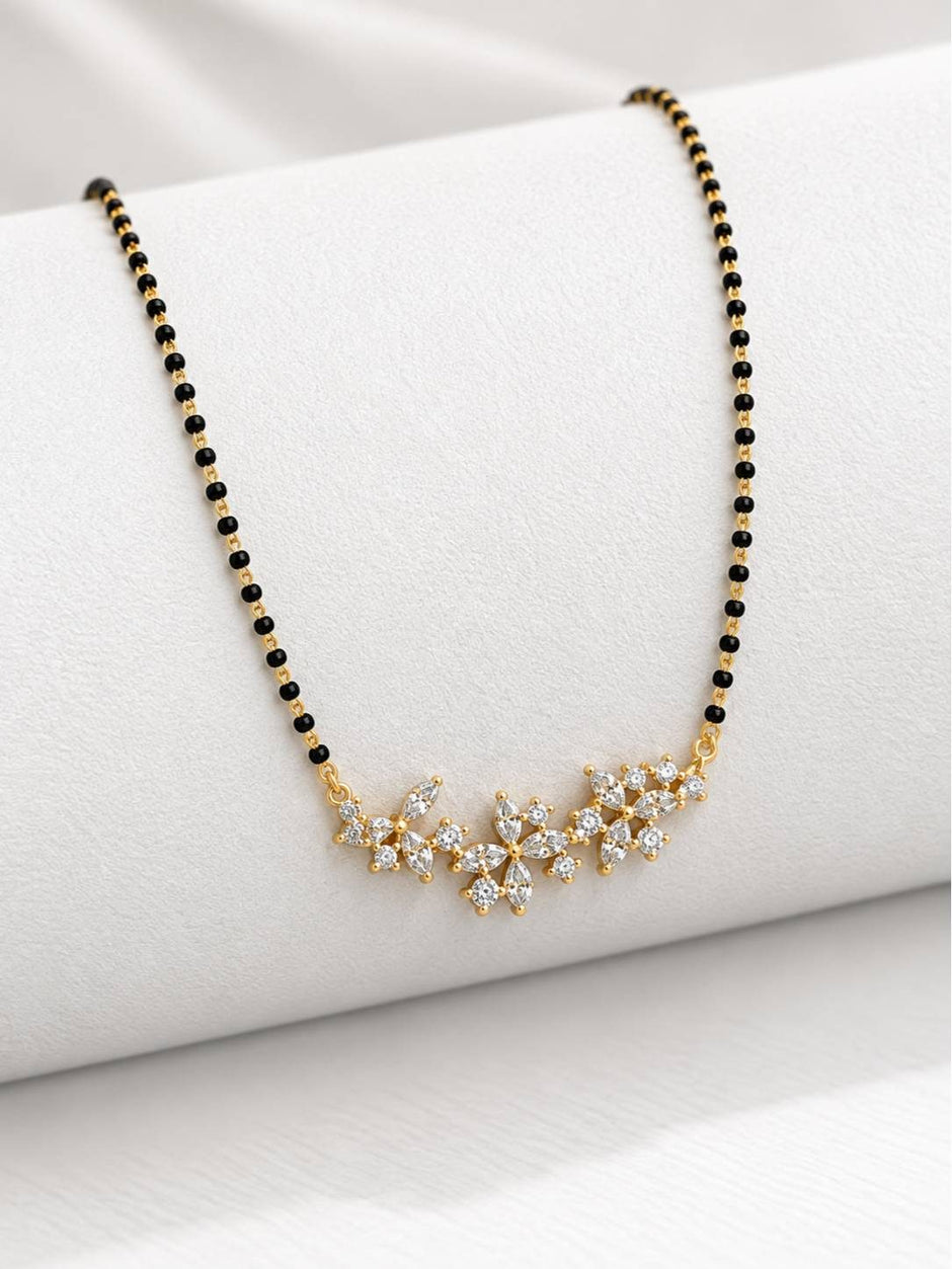 Close-up of three CZ flower pendant motifs on gold-plated mangalsutra draped over a white roll