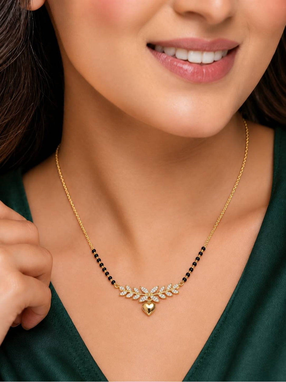 Woman wearing gold-plated CZ mangalsutra with heart pendant over a dark green outfit