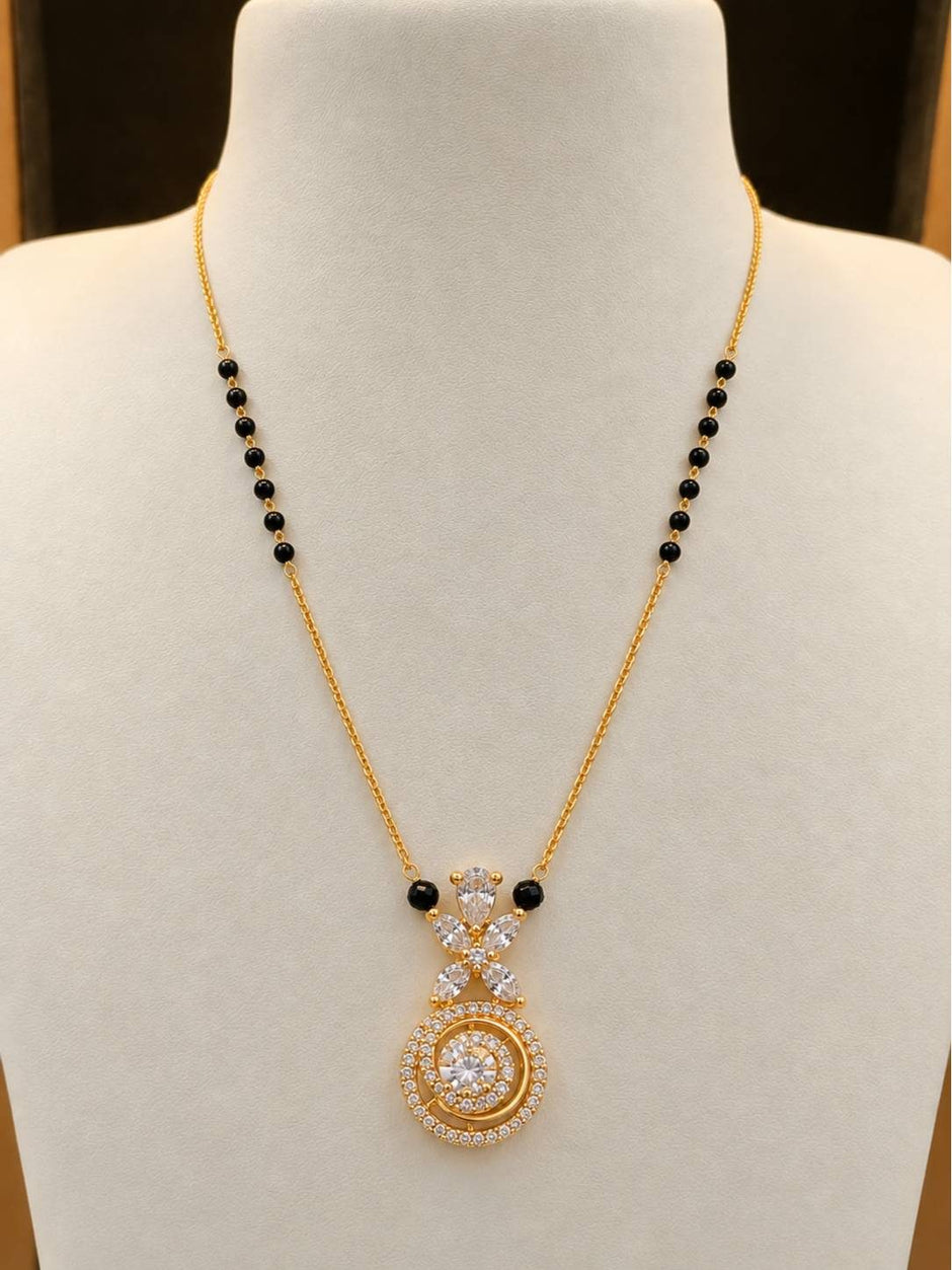 Gold-plated CZ mangalsutra with black beads displayed on a white jewellery bust