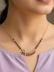 Model wearing gold-plated black bead mangalsutra with purple stone pendant over a lavender kurta