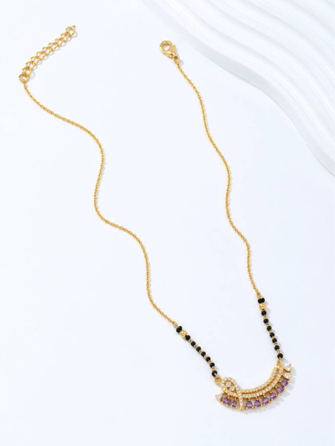 Full length flat lay of gold-plated mangalsutra chain with black beads, extender links and lobster clasp closure