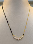 Gold-plated CZ mangalsutra on a cream jewellery bust showing black bead strand and gold chain