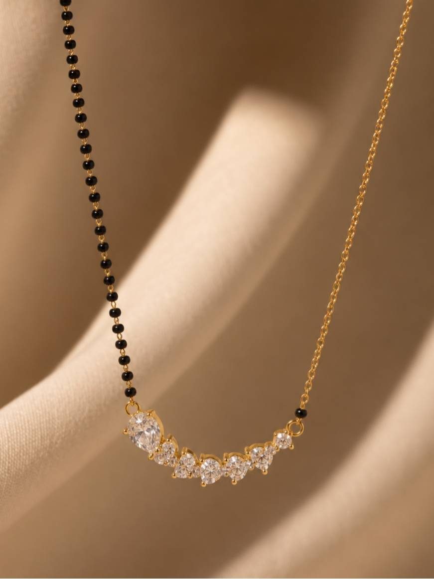 Close-up of curved CZ bar pendant with pear and round stones on draped fabric background