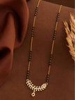 Full-length view of gold-plated CZ mangalsutra laid flat on a brown draped fabric with dried grass styling prop