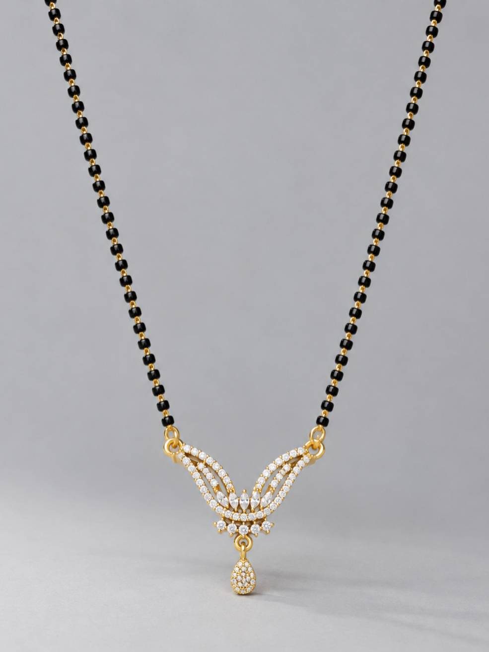 Front view of black bead mangalsutra with cubic zirconia pendant on grey background