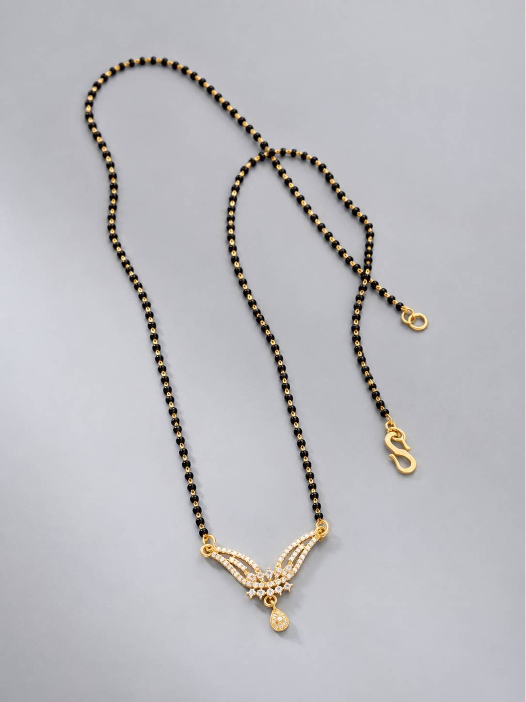 Full length flat lay of black bead mangalsutra showing S-hook clasp and CZ pendant