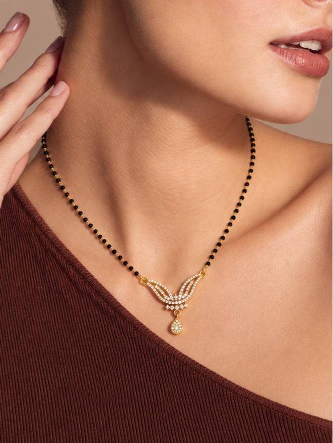 Woman wearing gold-plated CZ mangalsutra over a dark red ribbed top