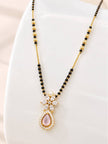 Close-up of mangalsutra pendant on a white curved display stand showing marquise CZ flower, pearl, and rose cabochon teardrop in gold frame
