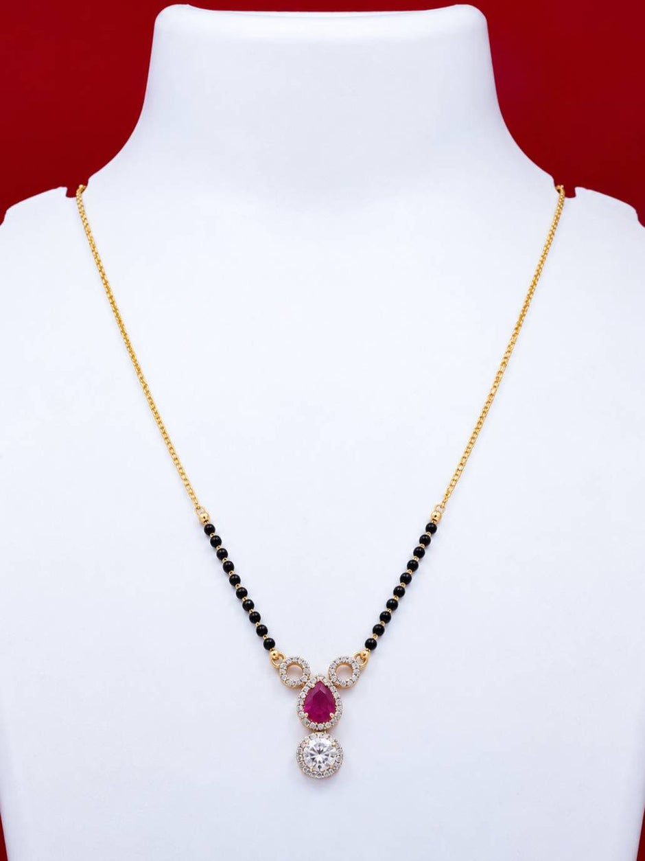 Gold-plated mangalsutra with fuchsia CZ pear pendant and white round CZ displayed on a white jewellery bust against a red background