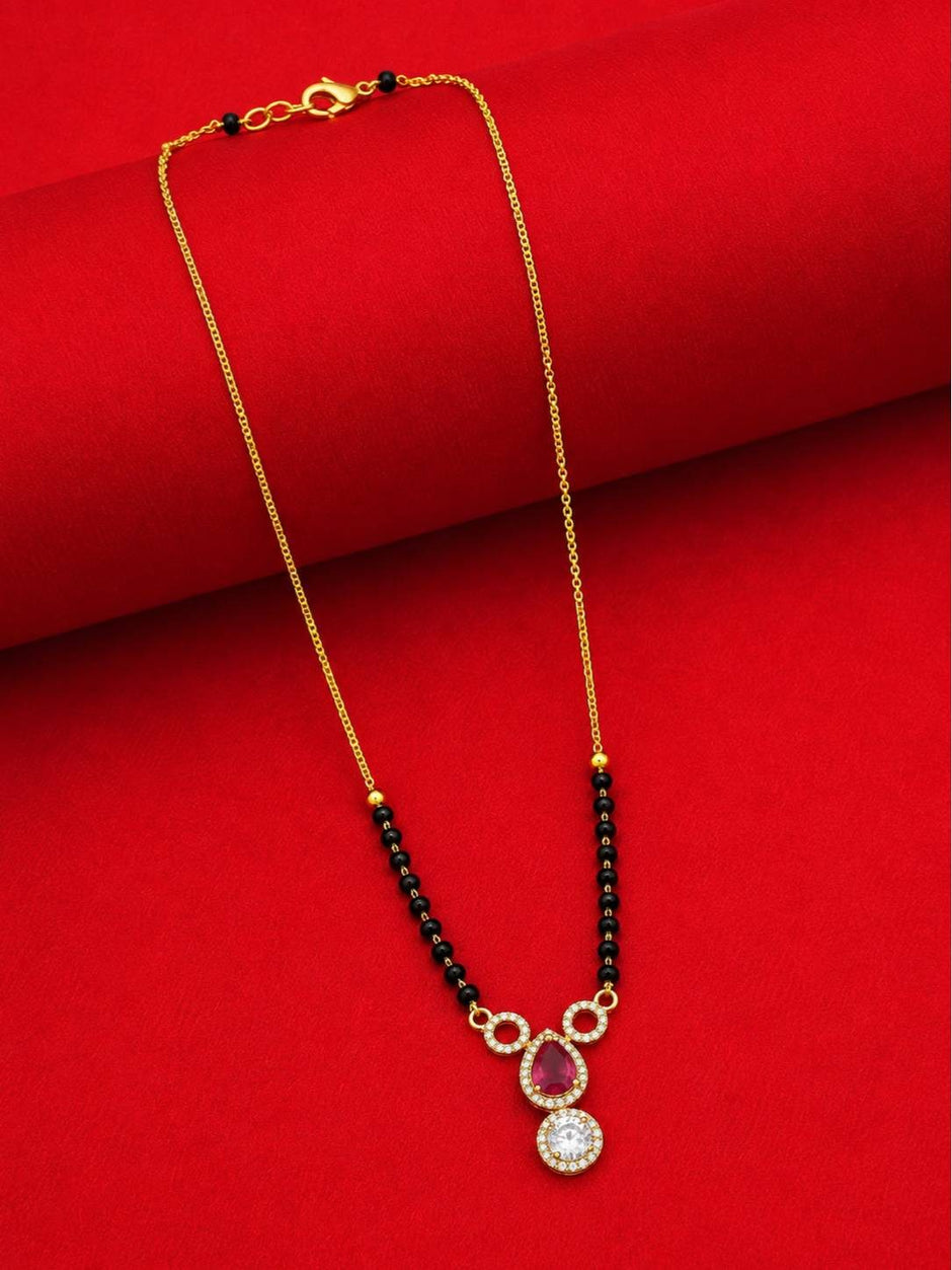 Full-length view of gold-plated black bead mangalsutra laid flat on red fabric showing lobster clasp and full chain length