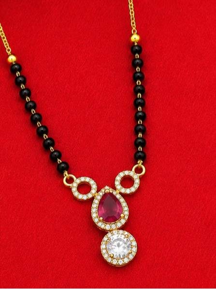Close-up of mangalsutra pendant showing open ring motifs, fuchsia pear CZ stone, and white solitaire CZ drop on black bead chain