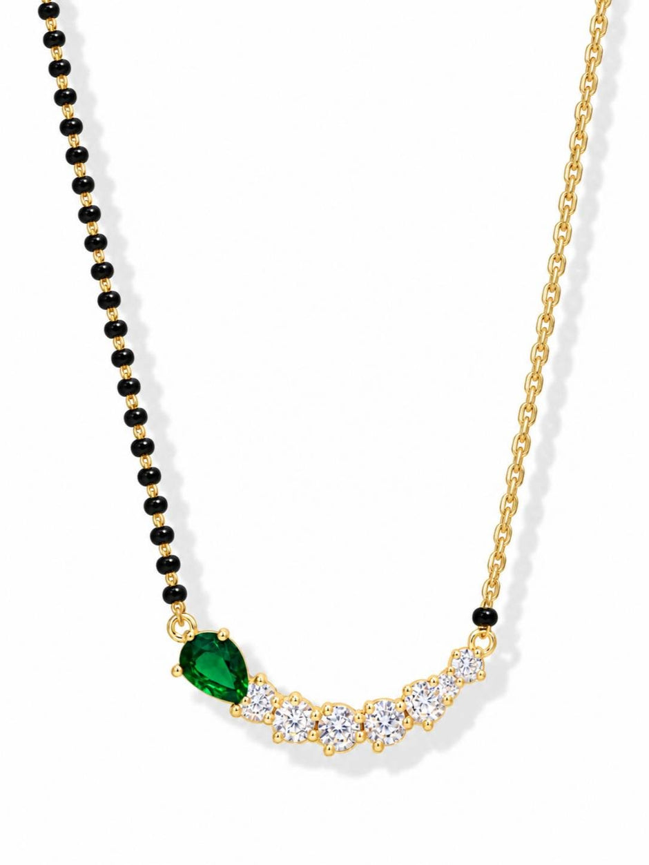Close-up of gold-plated mangalsutra on white background showing pear-cut green stone and round white CZ pendant