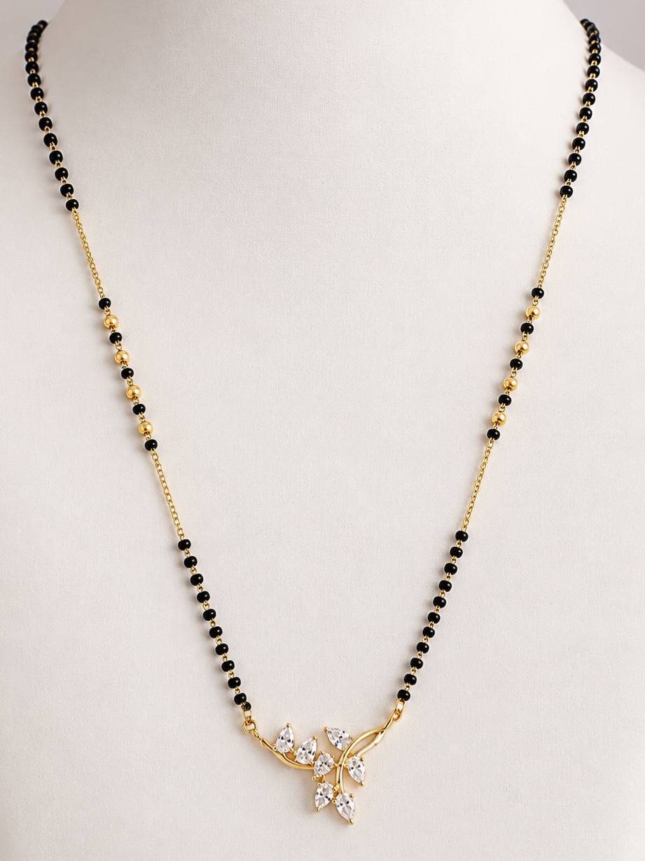 Gold-plated CZ leaf mangalsutra with black and gold beads displayed on a white jewellery bust