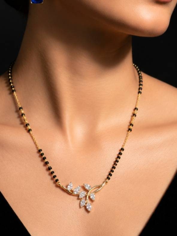 Gold-plated black bead mangalsutra with CZ leaf pendant worn around a woman's neck