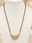 Gold-plated CZ mangalsutra with black beads displayed on a white jewellery bust