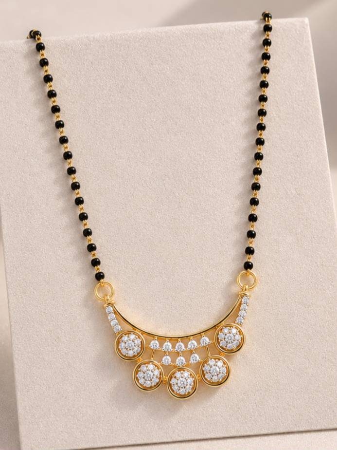 Close-up of CZ crescent pendant with five circular clusters on gold mangalsutra chain laid flat