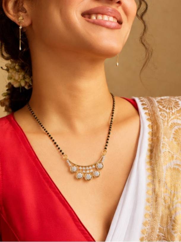 Woman wearing gold-plated CZ mangalsutra with red and white saree, smiling