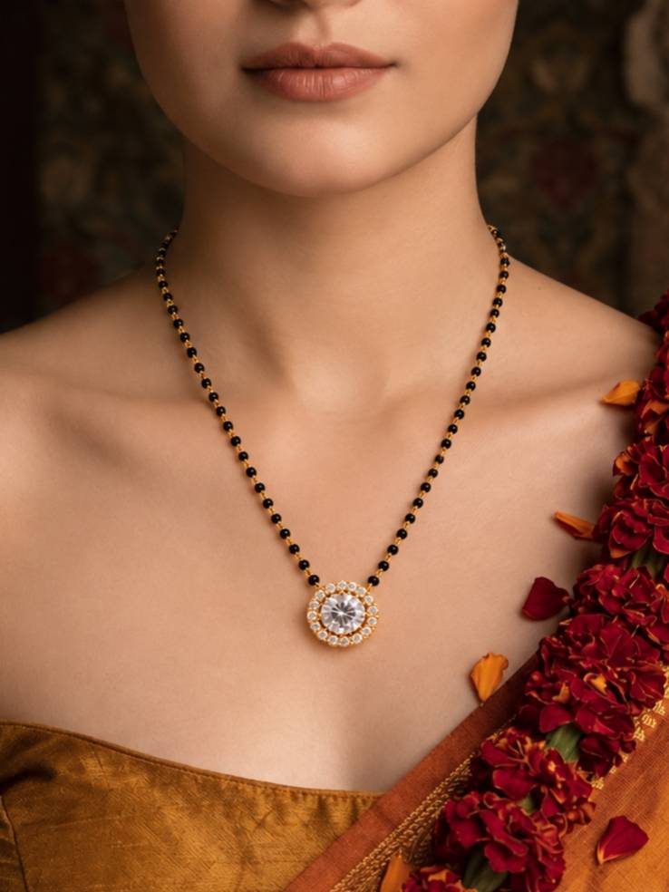 Woman wearing gold-plated CZ mangalsutra over a gold silk saree with red floral garland in background
