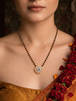 Woman wearing gold-plated CZ mangalsutra over a gold silk saree with red floral garland in background