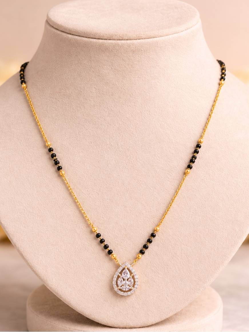 Gold-plated CZ mangalsutra with teardrop pendant displayed on a beige jewellery bust
