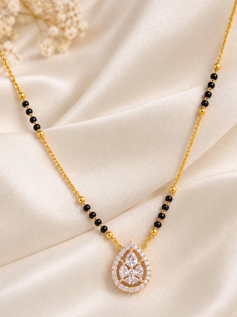 CZ mangalsutra with black bead chain and teardrop pendant laid flat on cream satin fabric
