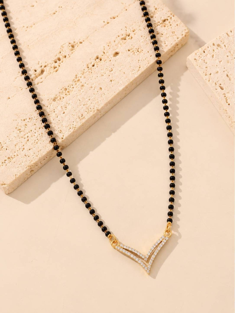 Double V cubic zirconia mangalsutra laid flat on a textured travertine stone surface