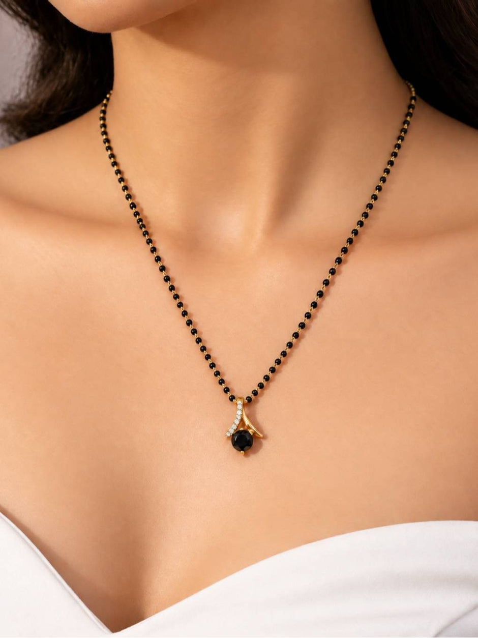 Close-up of black bead mangalsutra with gold and black stone pendant worn around a woman's neck