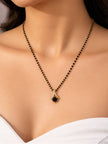 Close-up of black bead mangalsutra with gold and black stone pendant worn around a woman's neck