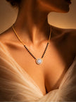 Model wearing gold-plated black bead mangalsutra with CZ pendant against a warm beige background