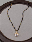 Close-up of black bead mangalsutra with gold twisted bail and round cubic zirconia pendant on a round display tray