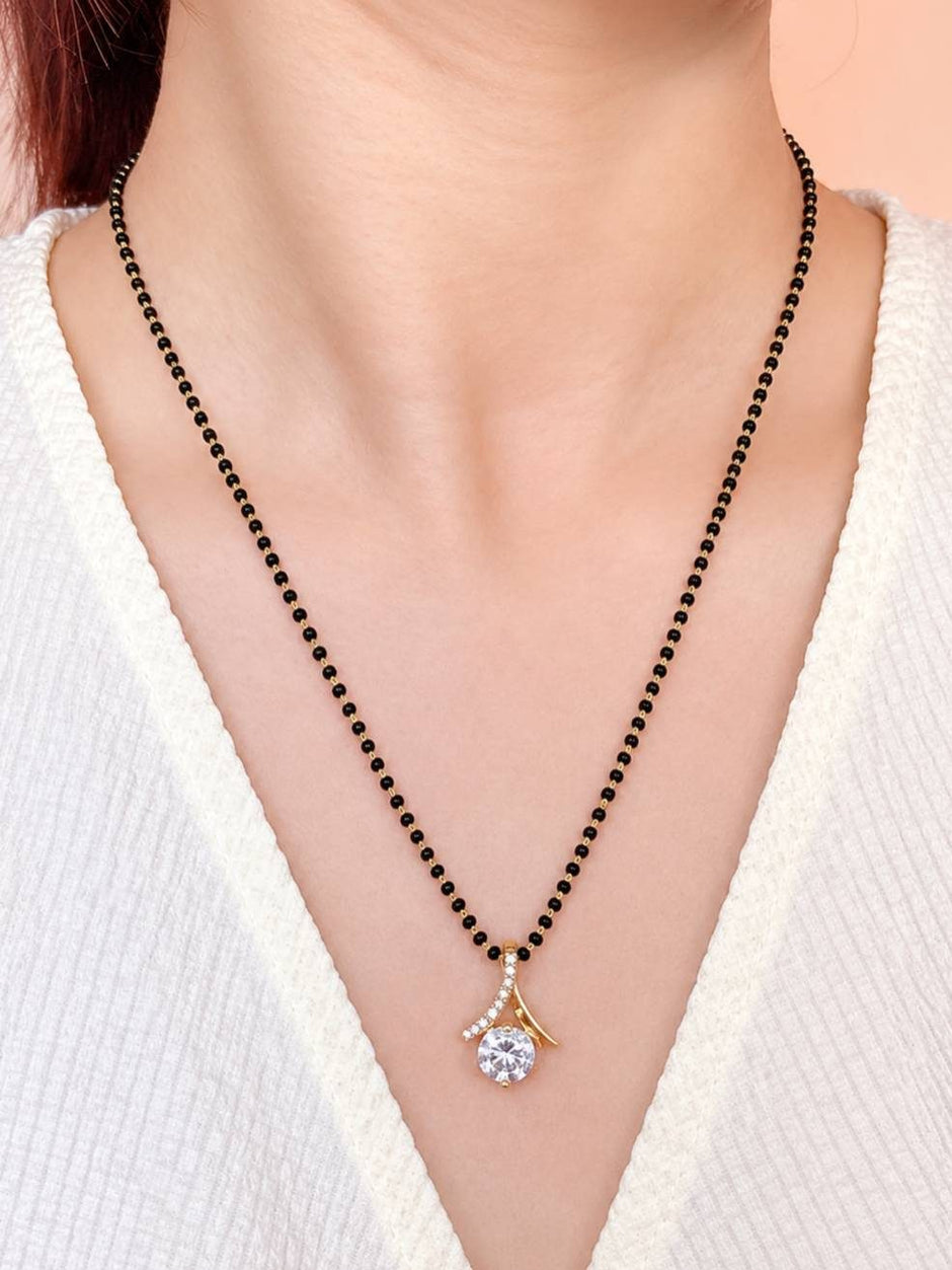 Model wearing gold-plated black bead mangalsutra with CZ pendant over a white ribbed top