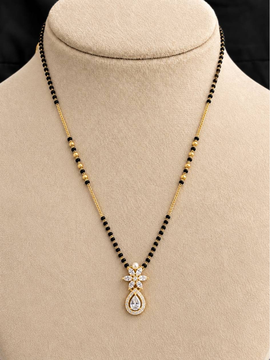 Gold-plated mangalsutra with black beads and CZ pearl pendant displayed on a cream jewellery bust