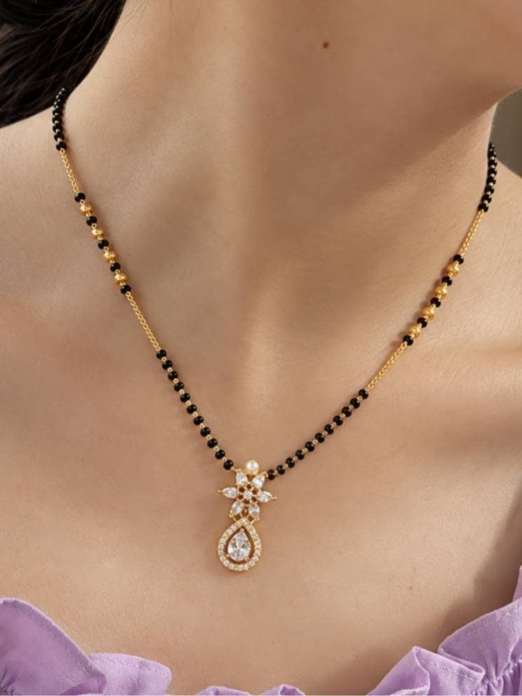 Gold-plated black bead mangalsutra with CZ and pearl pendant worn around a woman's neck
