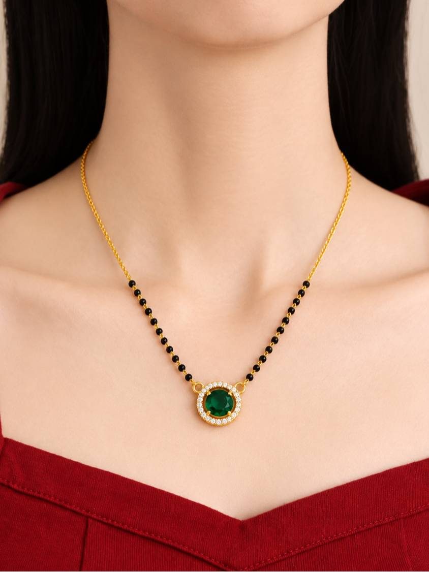 Model wearing gold-plated green CZ mangalsutra over a red top showing pendant at collarbone