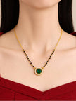 Model wearing gold-plated green CZ mangalsutra over a red top showing pendant at collarbone