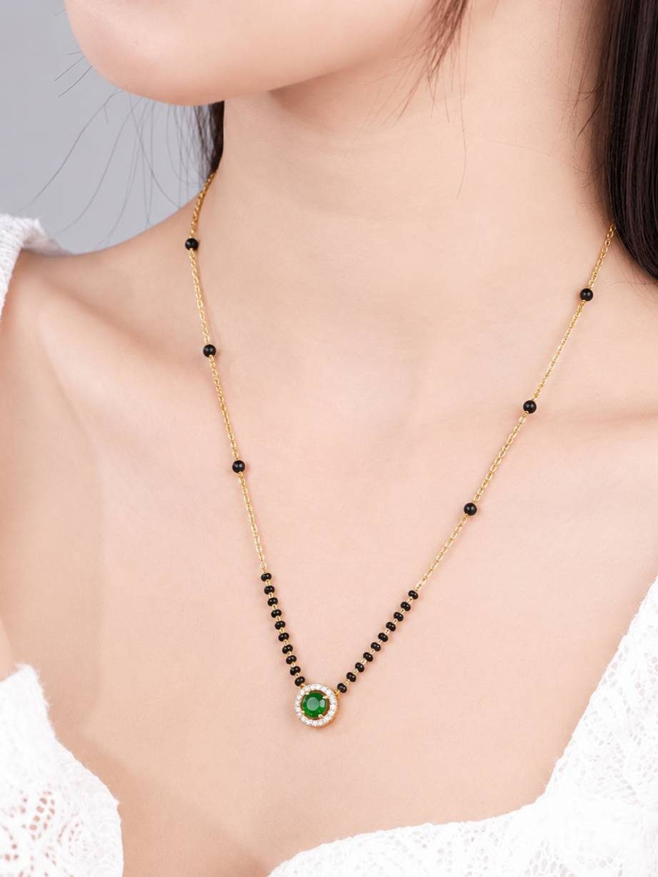 Gold-plated emerald CZ mangalsutra worn around a woman's neck showing drape and pendant detail