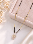 Mangalsutra with black bead chain and floral CZ pendant laid flat on a velvet jewellery tray with dried flowers