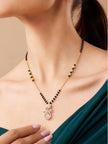 Woman wearing gold-plated black bead mangalsutra with pink CZ pendant over a teal off-shoulder outfit