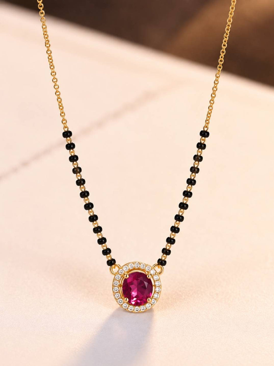 Ruby CZ mangalsutra pendant with black bead strands laid flat on peach marble surface